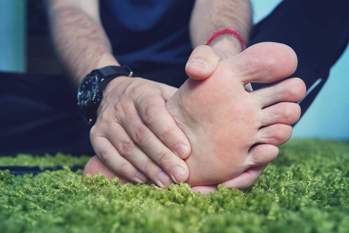 Man with painful and inflamed gout on his foot around the big toe area. Man's hand being massaged a foot